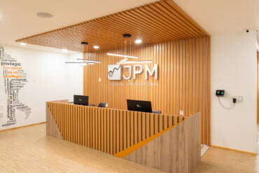 Arquitectura Comercial CDMX: recepción de oficinas JPM con layout funcional, mobiliario a medida, plafón de madera e iluminación de acento.
